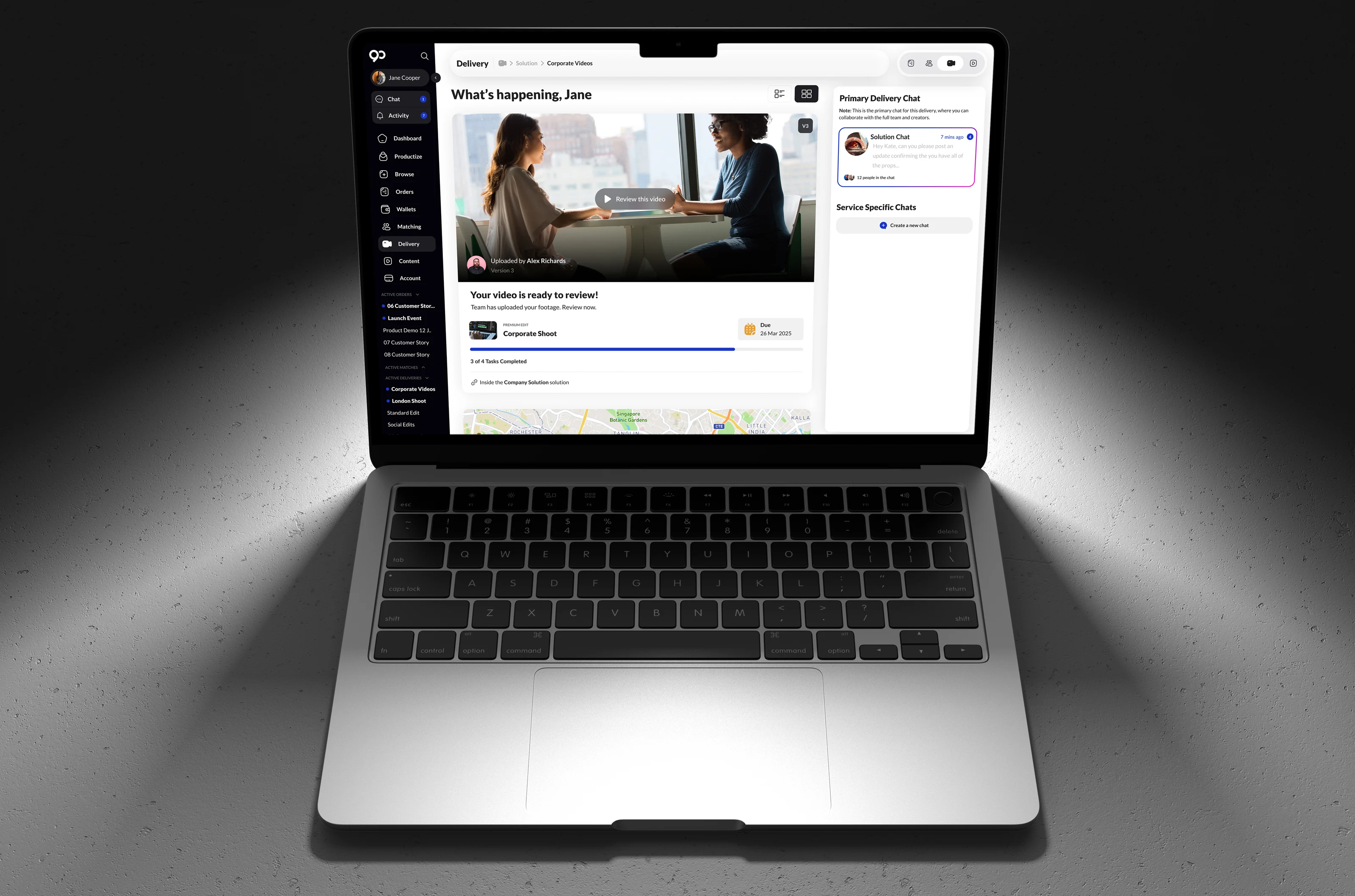 90 Seconds delivery workspace on a laptop. The page greets Jane, shows a ready-to-review corporate shoot video, a due date, task progress, map context, and a right-side primary delivery chat for production coordination.