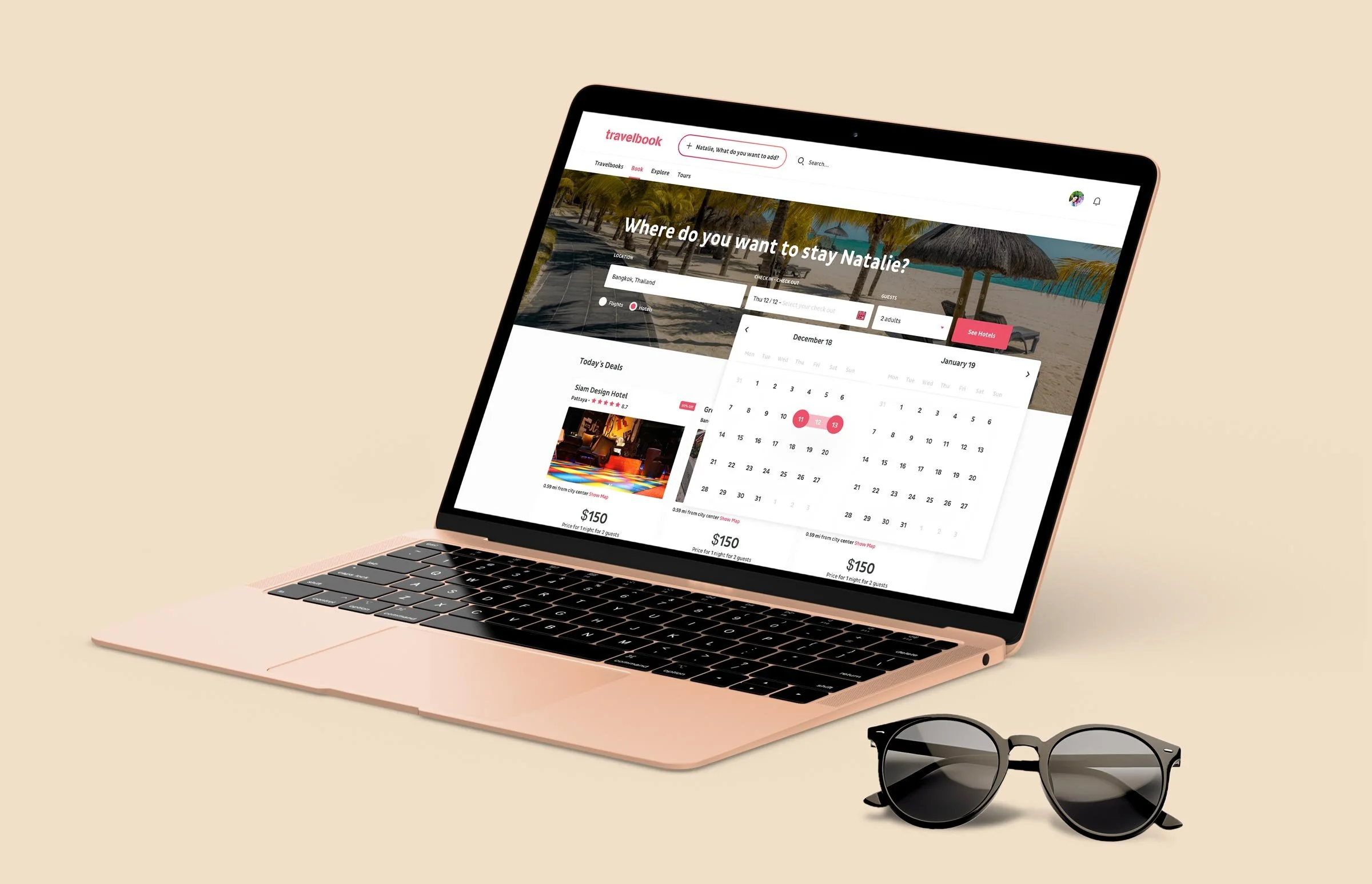 Travelbook hotel booking on a MacBook (rose-gold finish) sitting beside a pair of round black sunglasses. The hero is a beach scene asking "Where do you want to stay Natalie?" with three booking fields (Location set to Bangkok, Thailand; Check-in / Check-out; Guests at 2 adults) and a pink "See Hotels" CTA. A two-month date picker (December 18 to January 19) is open over the results, with a stay range pre-selected. A "Today's Deals" row shows the Siam Design Hotel and other rooms at $150 below the picker.